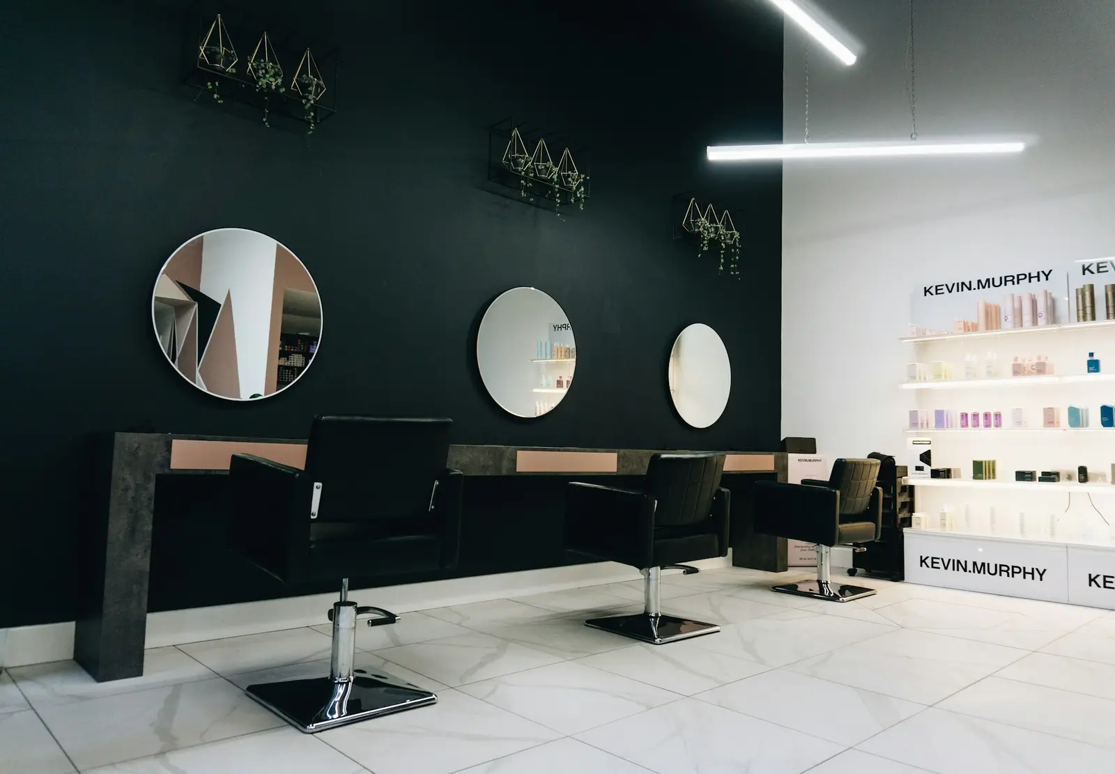 Intérieur du salon : fauteuils noirs et miroirs ronds